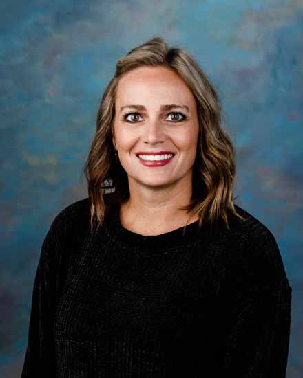 Portrait of Christina Walker, smiling with shoulder-length blonde hair, wearing a black sweater.