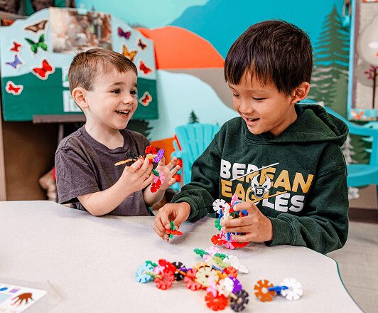 Young students build structures together during class with colorful building toys