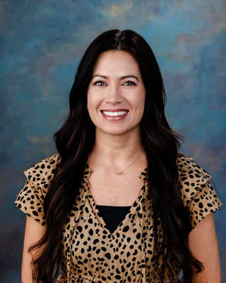 Portrait of Kelley Robison, smiling with long dark hair and a leopard print top.