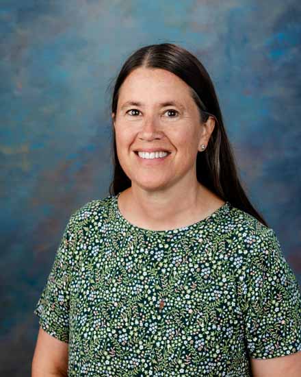 Linda Erhart, smiling woman with long brown hair, wearing a floral top.