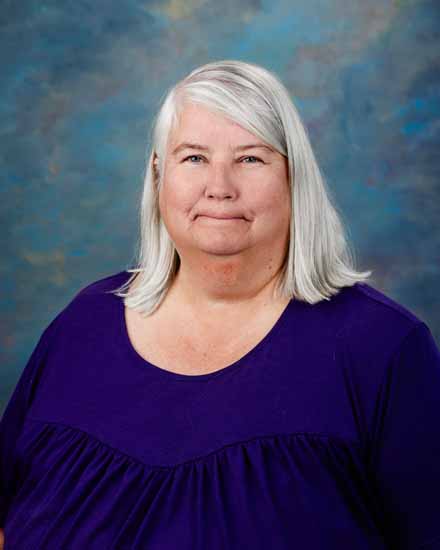 Lynnette Sluder portrait; woman with silver hair in purple top