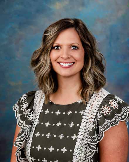 Professional headshot of Rachel Lozano with wavy hair, smiling confidently.