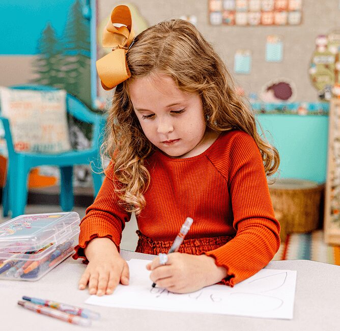 A young student works diligently on her artwork with colored pens