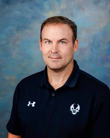 Steve Robison wearing a polo shirt with a logo, against a blue background.