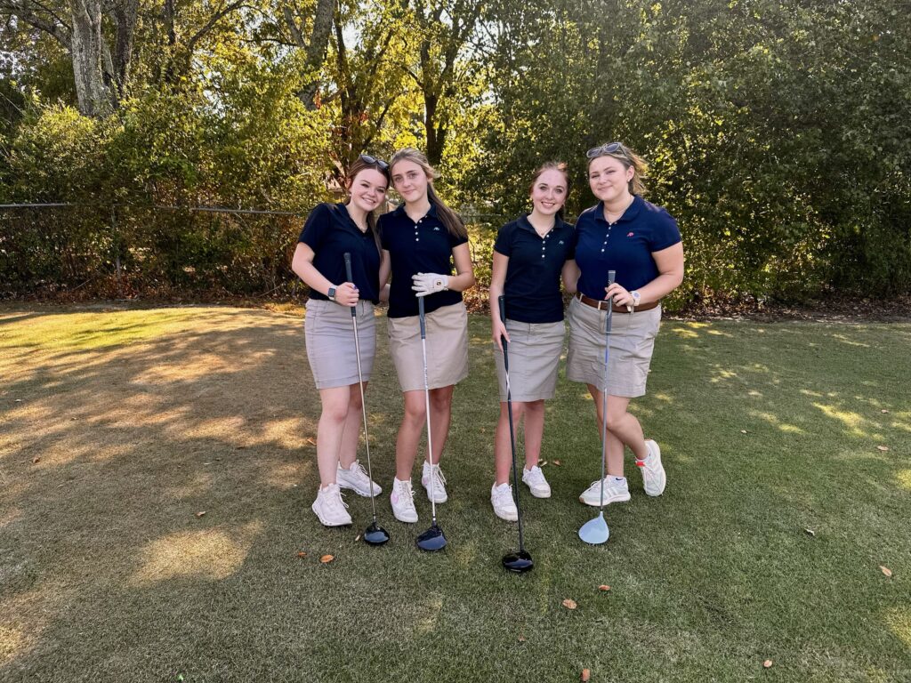 Girls golf team takes a photo at the tee with their drivers